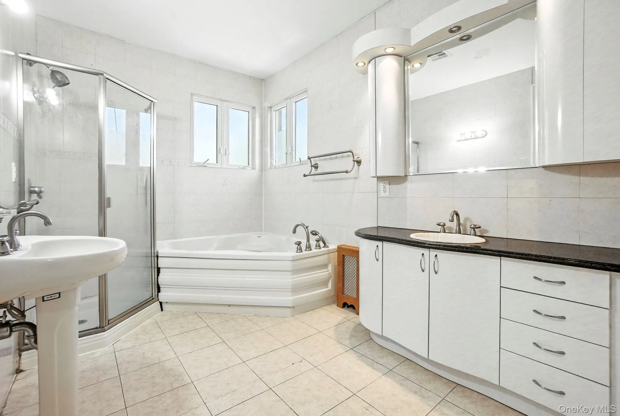 Full bath with a garden tub, light tile patterned floors, tile walls, a stall shower, and vanity Full bath with a garden tub, light tile patterned floors, tile walls, a stall shower, and vanity