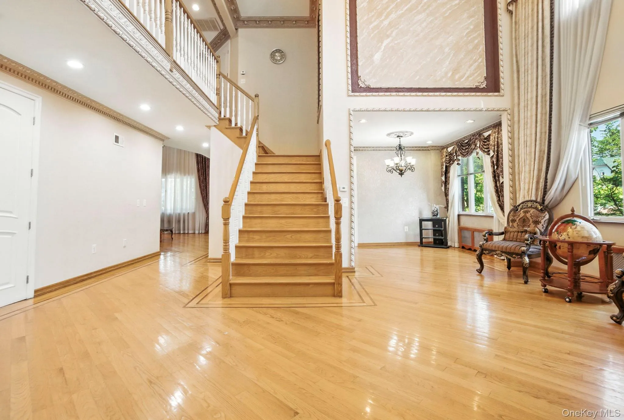 Stairway with a towering ceiling, wood finished floors, a chandelier, recessed lighting, and ornamental molding Stairway with a towering ceiling, wood finished floors, a chandelier, recessed lighting, and ornamental molding