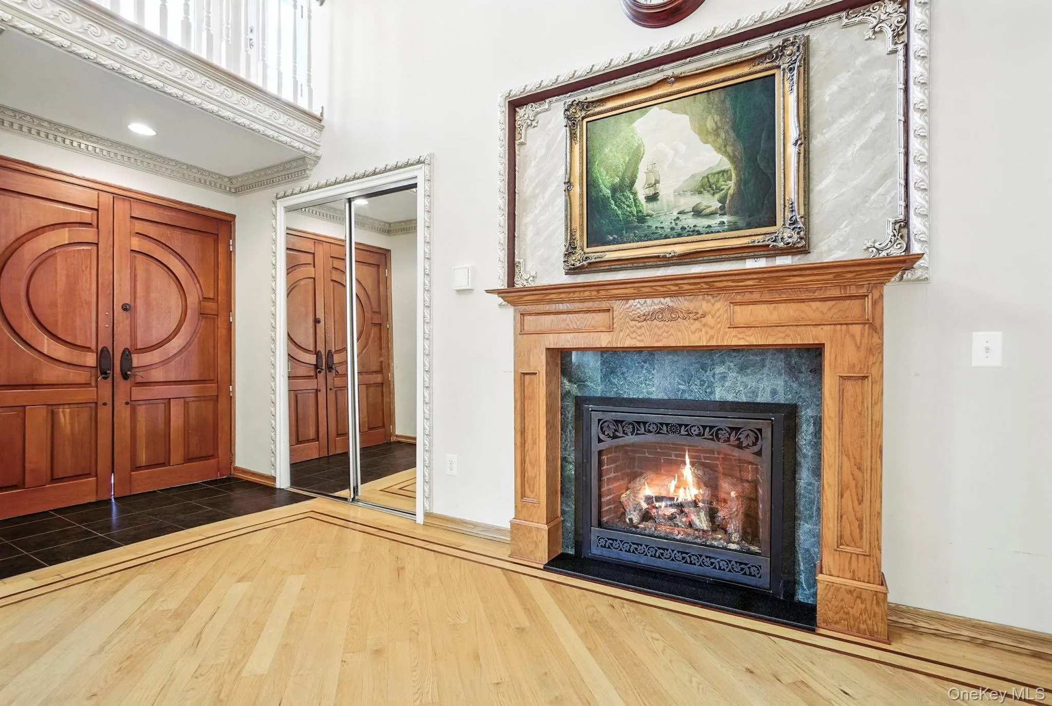 Foyer entrance featuring dark wood finished floors, a lit fireplace, and a high ceiling Foyer entrance featuring dark wood finished floors, a lit fireplace, and a high ceiling