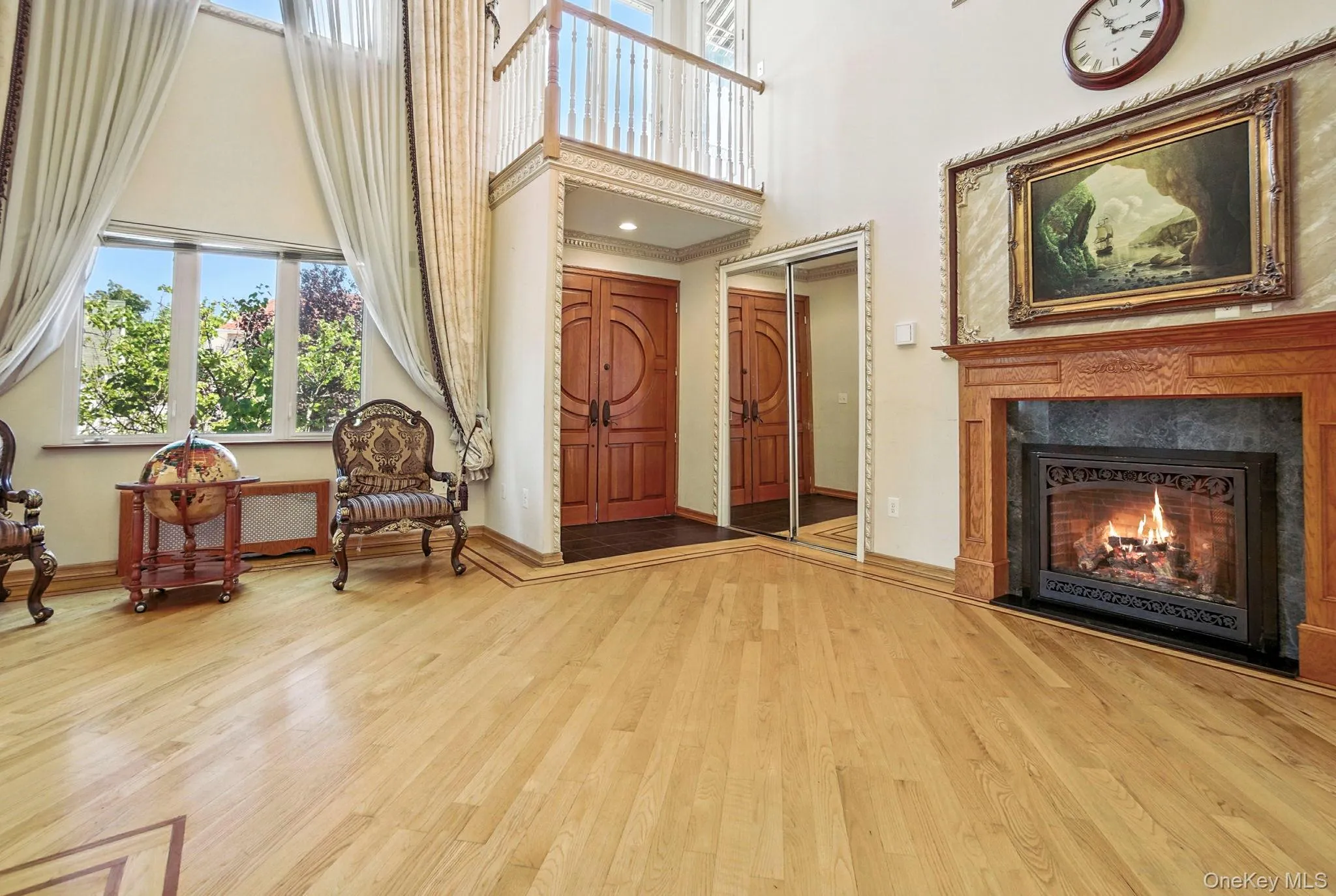Sitting room with a high ceiling, a lit fireplace, and light wood finished floors Sitting room with a high ceiling, a lit fireplace, and light wood finished floors