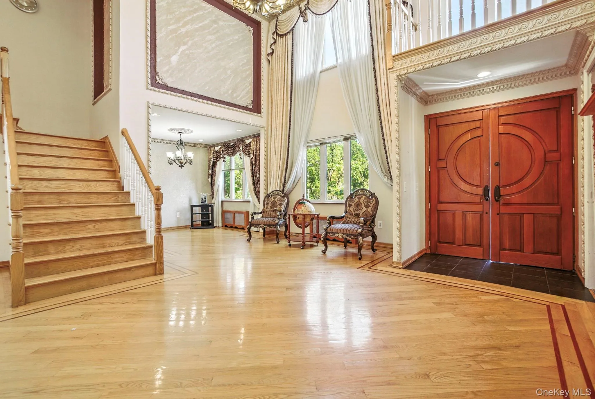 Entryway featuring a chandelier, dark wood-style floors, a towering ceiling, stairway, and crown molding Entryway featuring a chandelier, dark wood-style floors, a towering ceiling, stairway, and crown molding