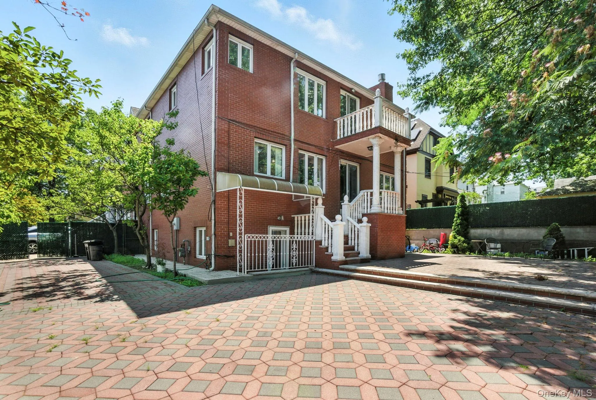 View of front of home with brick siding, a gate, and a balcony View of front of home with brick siding, a gate, and a balcony