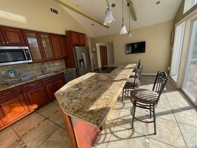 Kitchen featuring vaulted ceiling, a center island, stainless steel appliances, decorative backsplash, and sink Kitchen featuring vaulted ceiling, a center island, stainless steel appliances, decorative backsplash, and sink