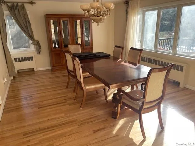 Dining room featuring radiator heating unit, light hardwood / wood-style floors, and a notable chandelier Dining room featuring radiator heating unit, light hardwood / wood-style floors, and a notable chandelier