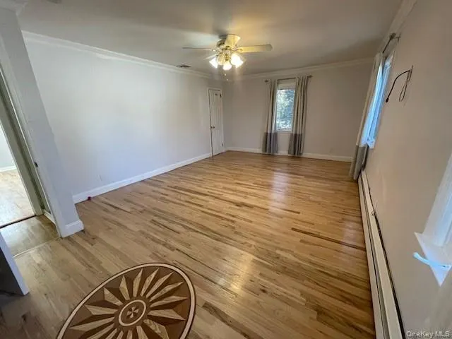 Unfurnished room featuring light hardwood / wood-style floors, ceiling fan, crown molding, and baseboard heating Unfurnished room featuring light hardwood / wood-style floors, ceiling fan, crown molding, and baseboard heating