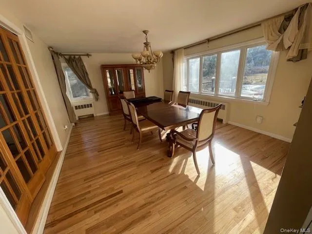 Dining area with a chandelier, light hardwood / wood-style flooring, and radiator heating unit Dining area with a chandelier, light hardwood / wood-style flooring, and radiator heating unit