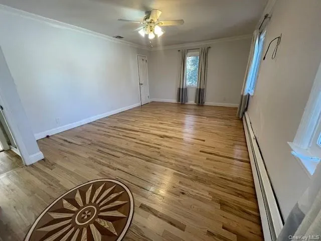 Empty room featuring ceiling fan, ornamental molding, and light hardwood / wood-style flooring Empty room featuring ceiling fan, ornamental molding, and light hardwood / wood-style flooring