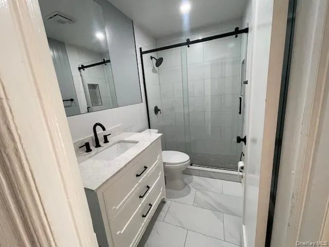 Bathroom featuring toilet, an enclosed shower, and vanity Bathroom featuring toilet, an enclosed shower, and vanity
