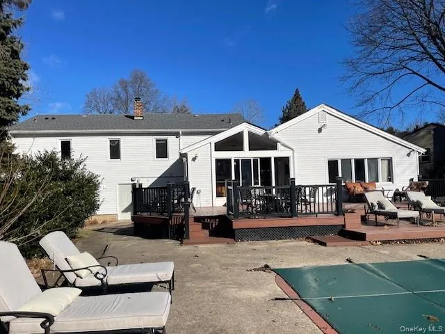 Rear view of property featuring a patio, a pool side deck, and a sunroom Rear view of property featuring a patio, a pool side deck, and a sunroom