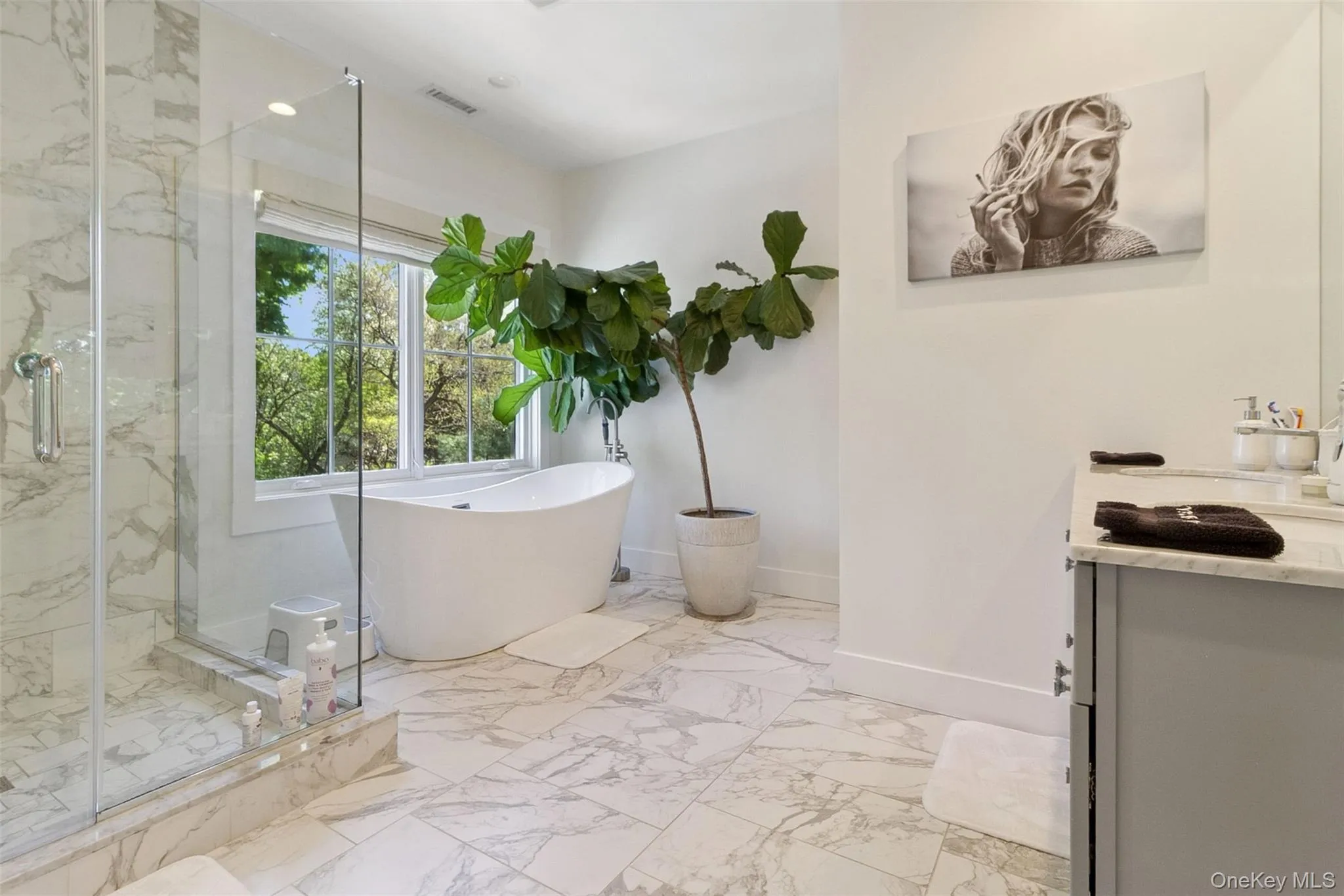 Full bathroom featuring vanity, a freestanding tub, light marble finish floors, and a marble finish shower Full bathroom featuring vanity, a freestanding tub, light marble finish floors, and a marble finish shower