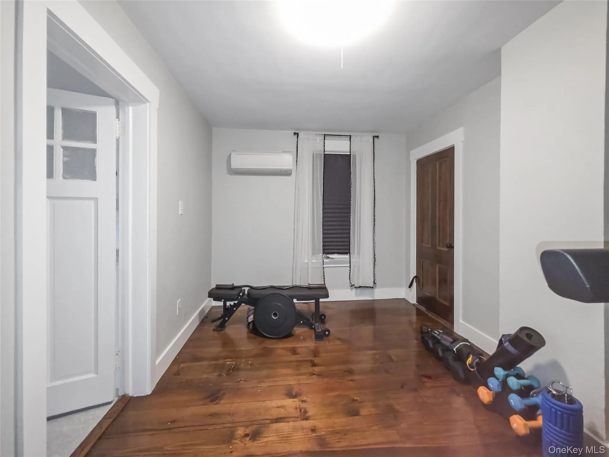 Exercise area with dark wood-type flooring and a wall unit AC Exercise area with dark wood-type flooring and a wall unit AC