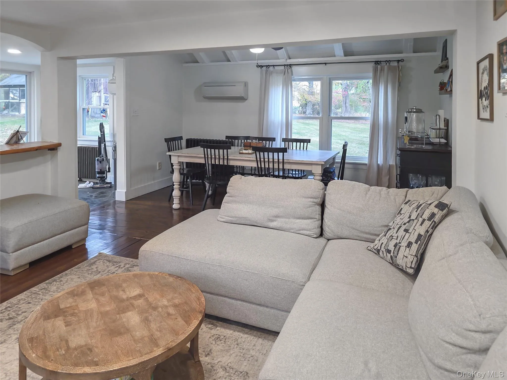 Living room with dark wood-style flooring, an AC wall unit, and radiator Living room with dark wood-style flooring, an AC wall unit, and radiator