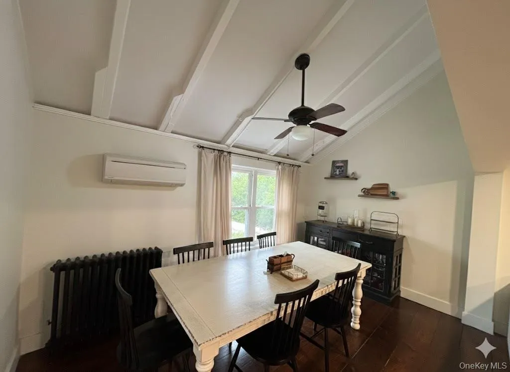 Dining area with radiator, dark wood-style floors, an AC wall unit, and a ceiling fan Dining area with radiator, dark wood-style floors, an AC wall unit, and a ceiling fan