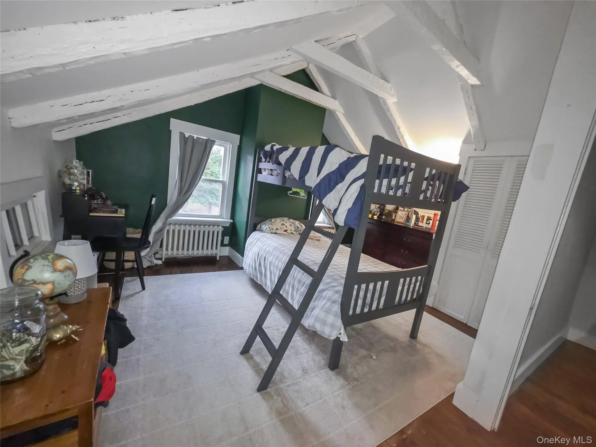 Bedroom with wood finished floors and radiator heating unit Bedroom with wood finished floors and radiator heating unit