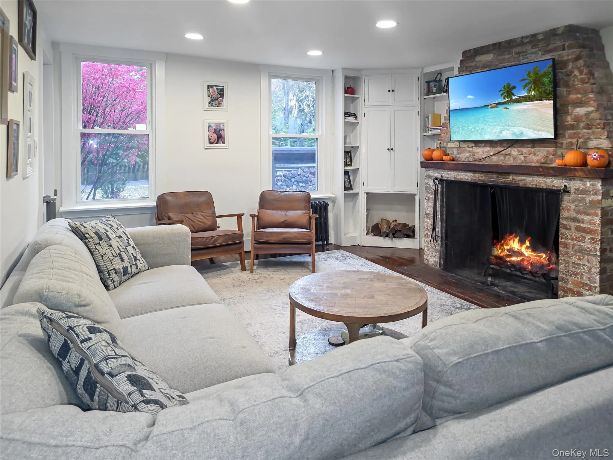Living area featuring a brick fireplace, recessed lighting, built in shelves, and wood finished floors Living area featuring a brick fireplace, recessed lighting, built in shelves, and wood finished floors