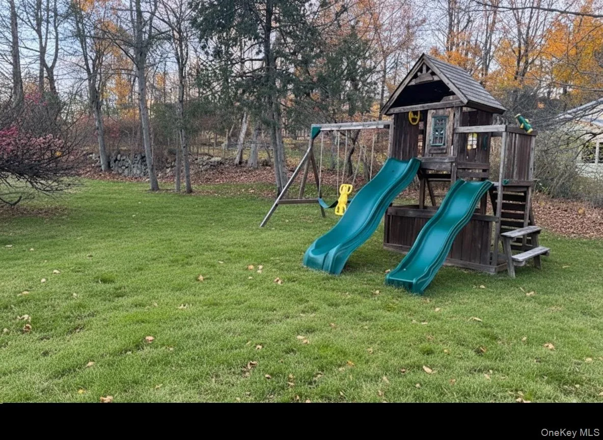 View of jungle gym featuring a lawn and view of scattered trees View of jungle gym featuring a lawn and view of scattered trees