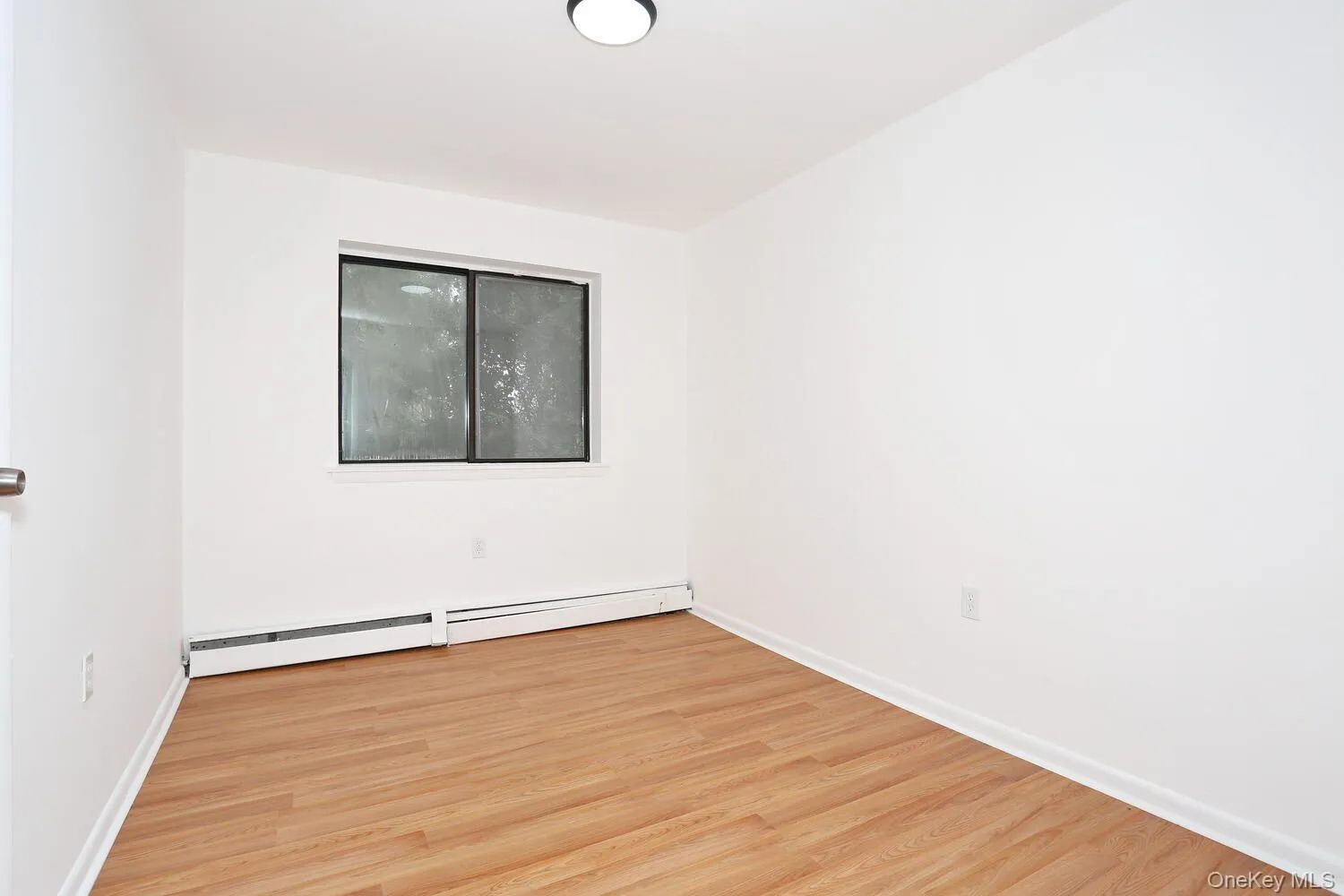 Spare room with light wood-type flooring and a baseboard heating unit Spare room with light wood-type flooring and a baseboard heating unit