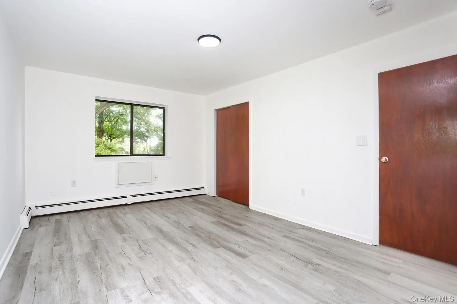 Spare room with light wood finished floors and a baseboard heating unit Spare room with light wood finished floors and a baseboard heating unit