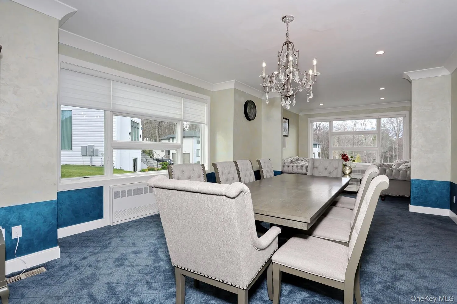 Dining room featuring radiator heating unit, dark colored carpet, ornamental molding, and a chandelier Dining room featuring radiator heating unit, dark colored carpet, ornamental molding, and a chandelier