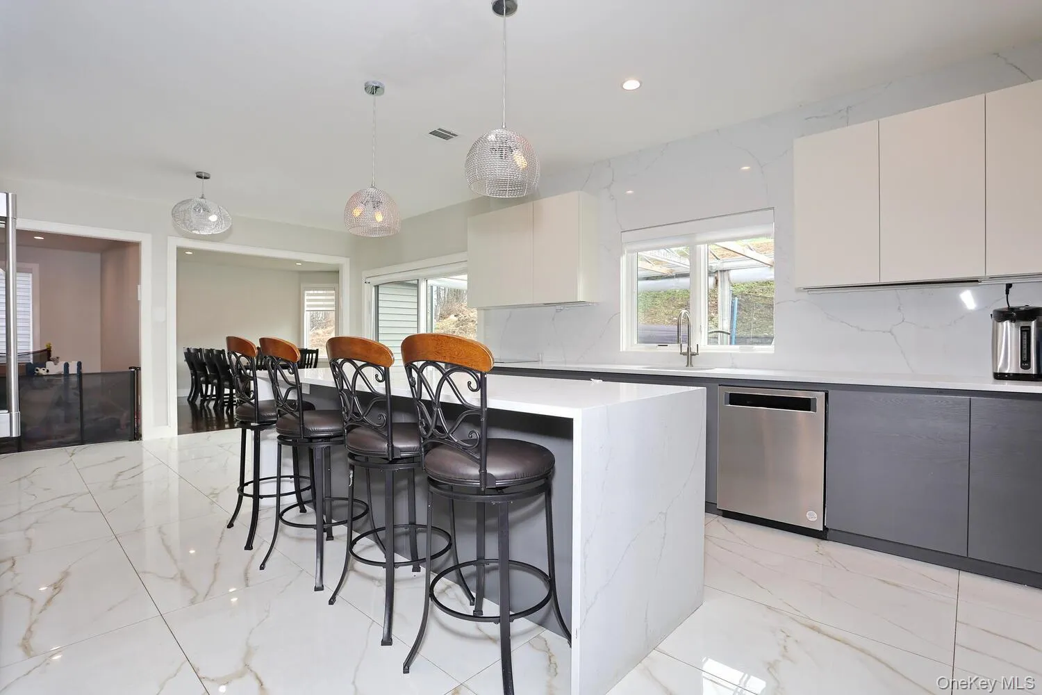 Kitchen featuring a kitchen bar, light marble finish floors, decorative light fixtures, white cabinets, and recessed lighting Kitchen featuring a kitchen bar, light marble finish floors, decorative light fixtures, white cabinets, and recessed lighting