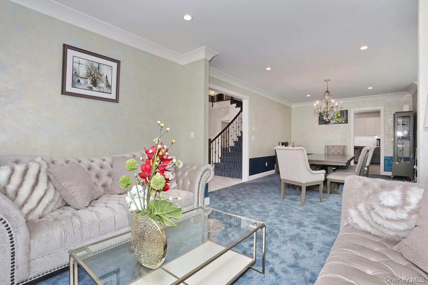 Living room with stairs, a chandelier, crown molding, recessed lighting, and carpet floors Living room with stairs, a chandelier, crown molding, recessed lighting, and carpet floors