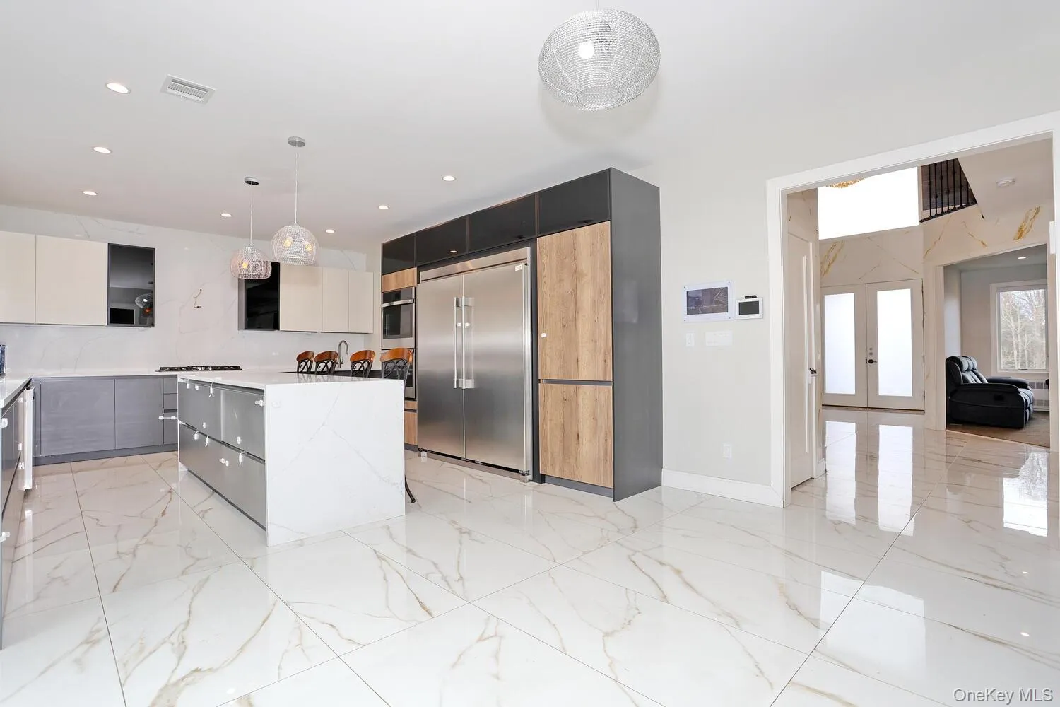 Kitchen featuring hanging light fixtures, modern cabinets, appliances with stainless steel finishes, a kitchen island, and gray cabinetry Kitchen featuring hanging light fixtures, modern cabinets, appliances with stainless steel finishes, a kitchen island, and gray cabinetry
