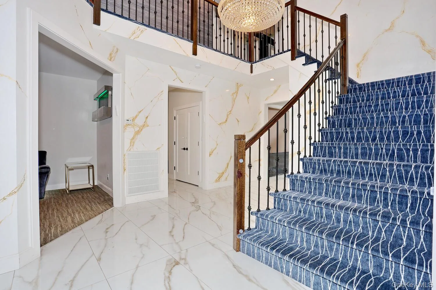 Stairway featuring a towering ceiling, marble tiled floors, a chandelier, and stone wall Stairway featuring a towering ceiling, marble tiled floors, a chandelier, and stone wall
