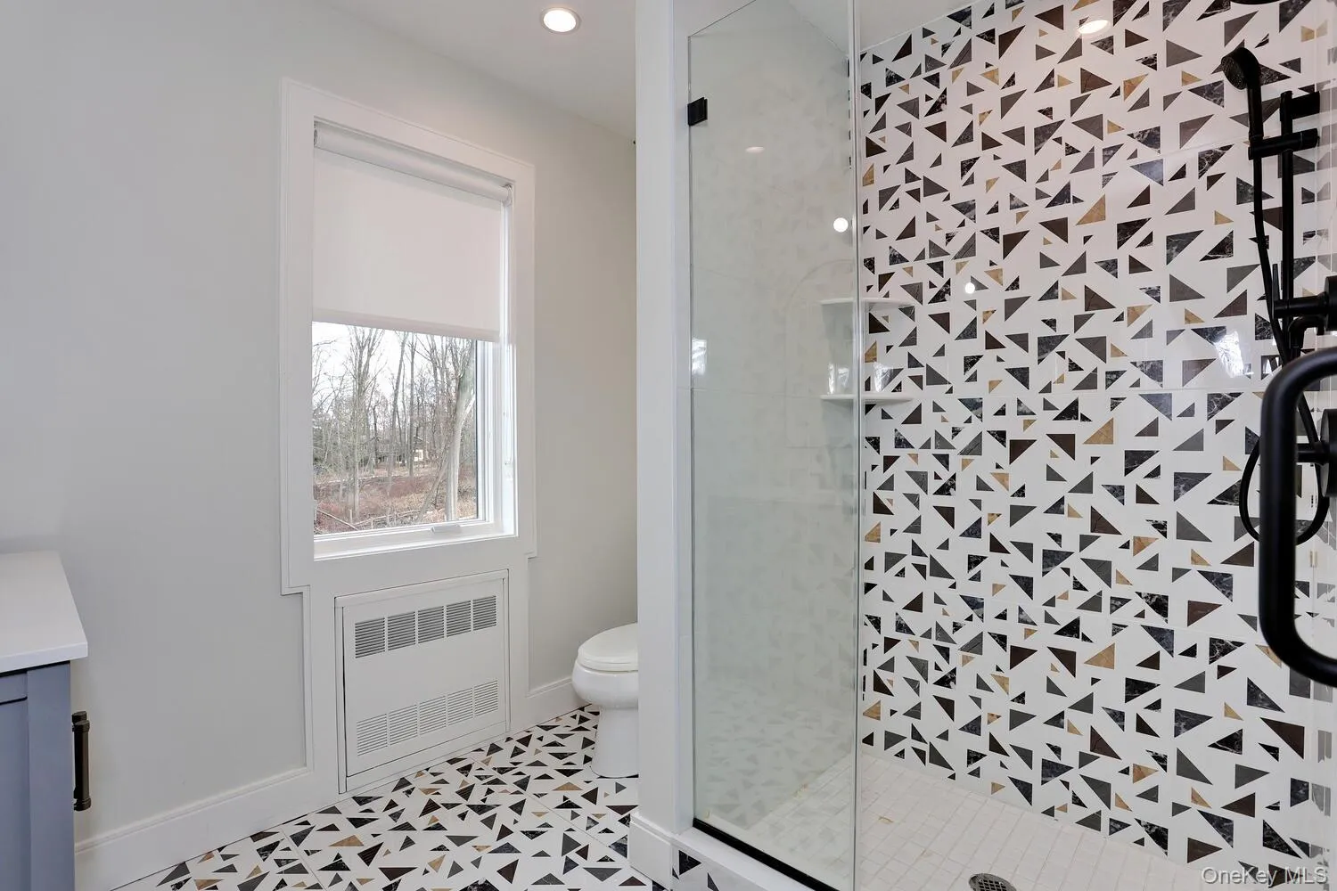 Full bath featuring vanity, a shower stall, and radiator heating unit Full bath featuring vanity, a shower stall, and radiator heating unit