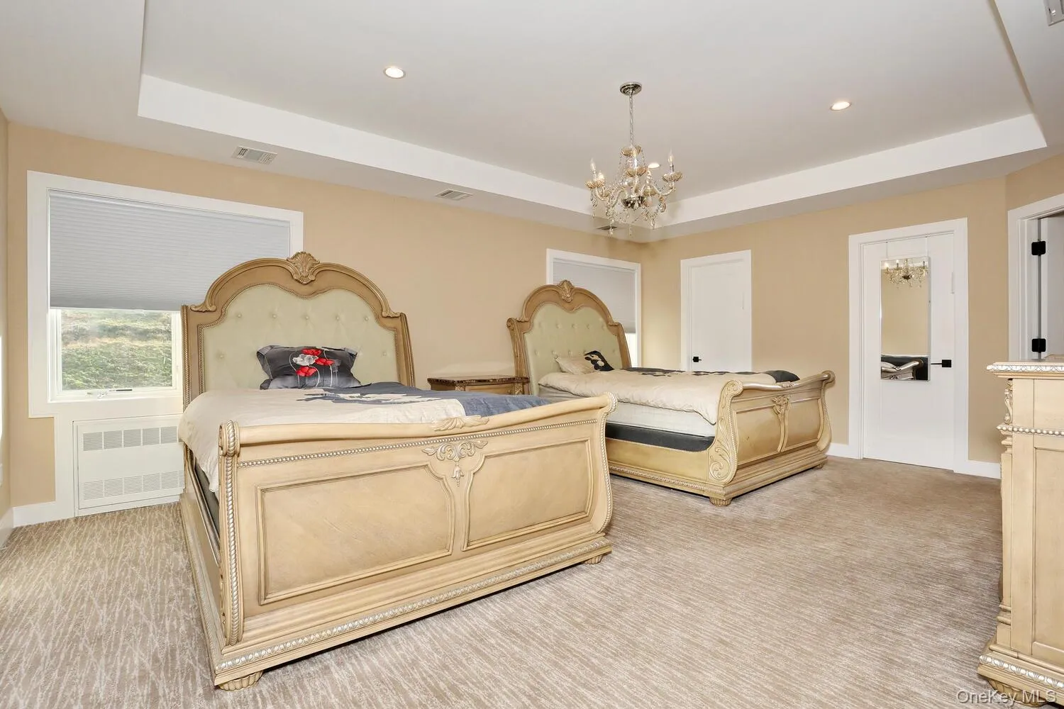 Bedroom featuring a raised ceiling, a chandelier, recessed lighting, and radiator heating unit Bedroom featuring a raised ceiling, a chandelier, recessed lighting, and radiator heating unit