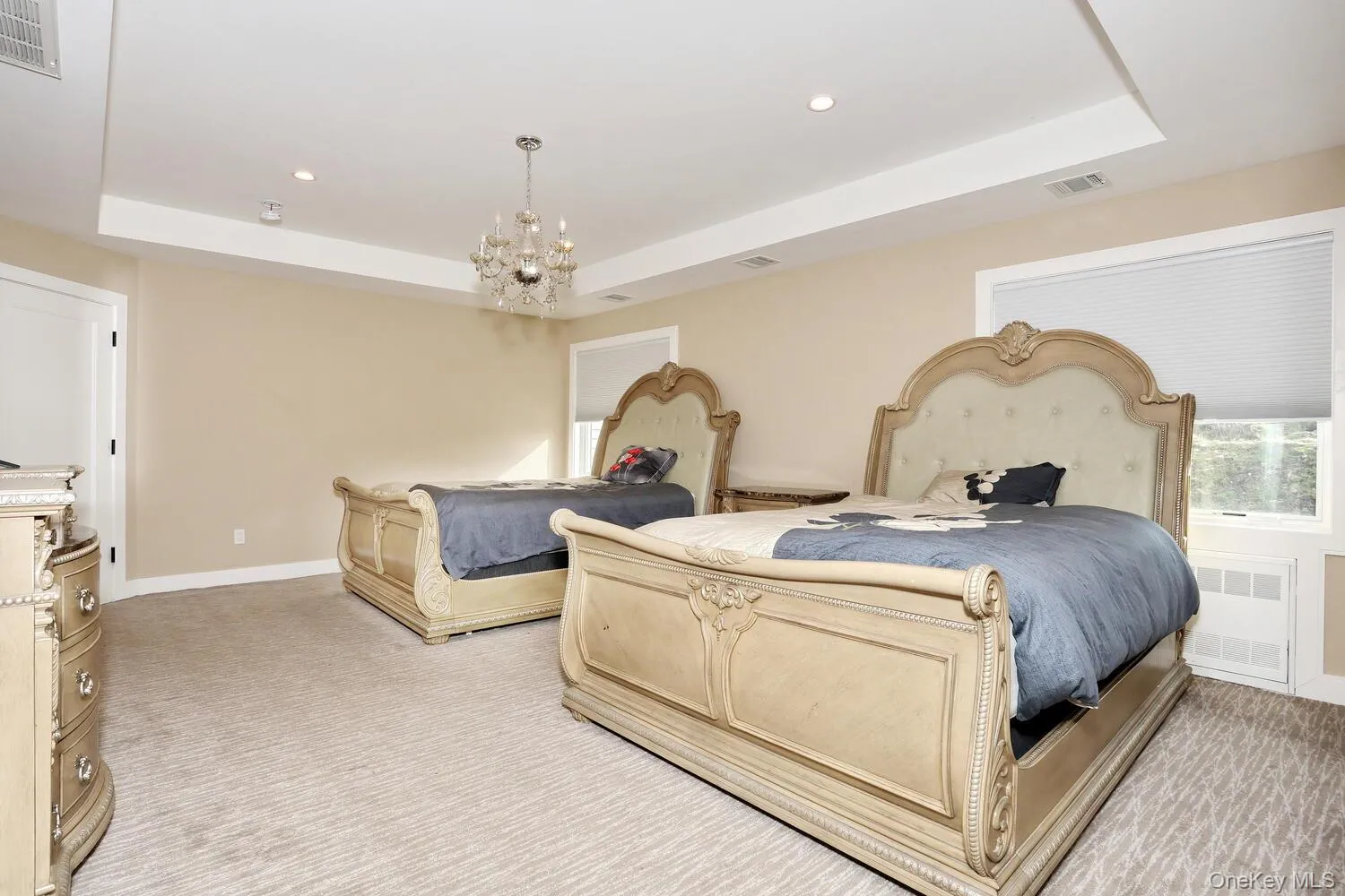 Bedroom featuring a tray ceiling, recessed lighting, light carpet, radiator, and a chandelier Bedroom featuring a tray ceiling, recessed lighting, light carpet, radiator, and a chandelier