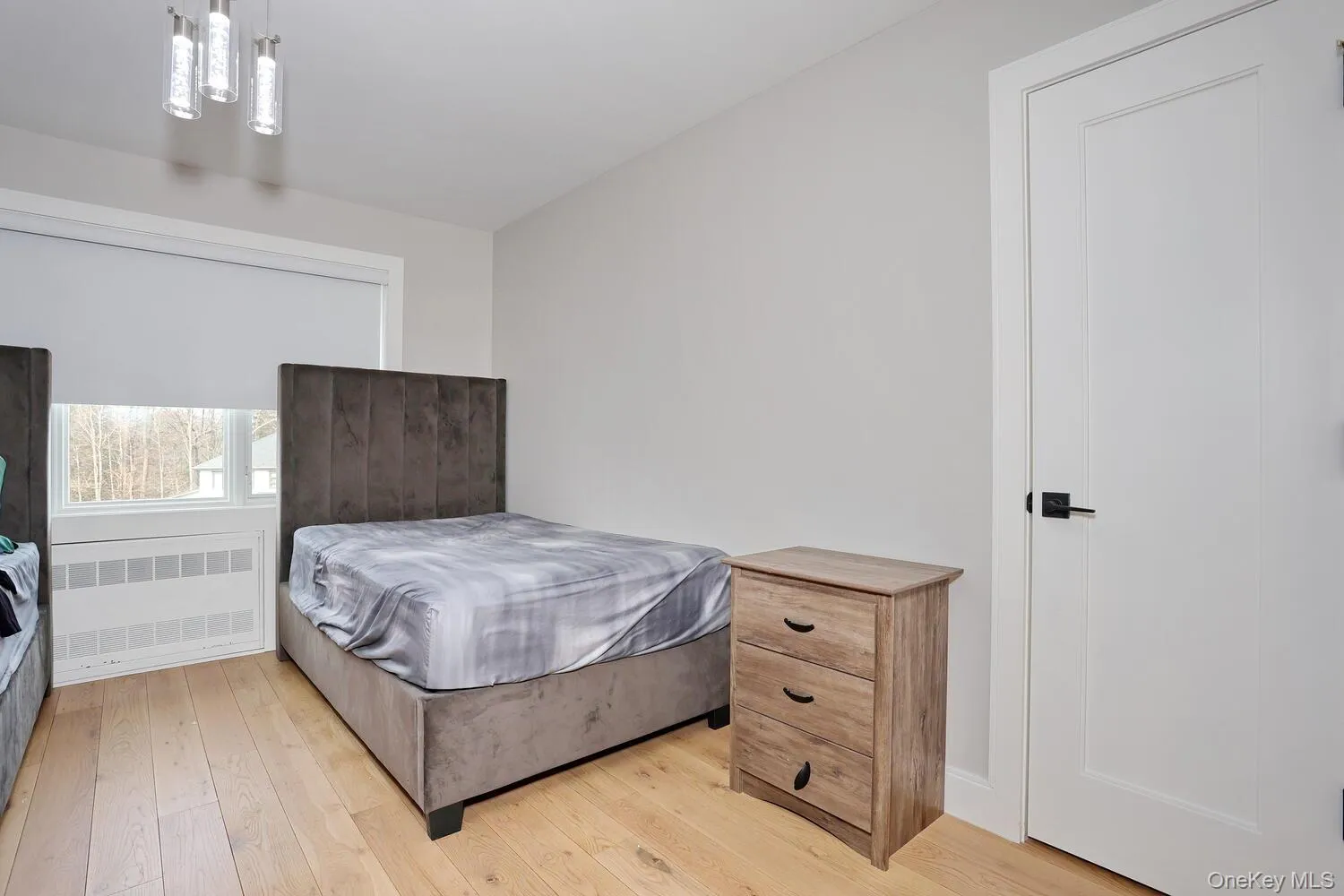 Bedroom with radiator and light wood finished floors Bedroom with radiator and light wood finished floors