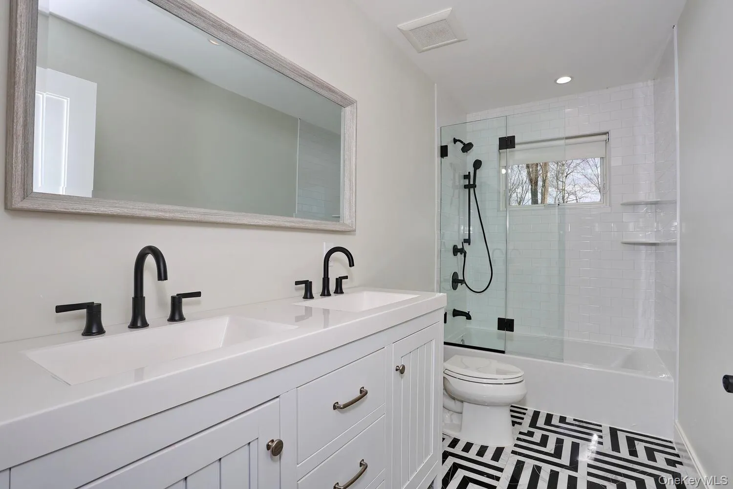 Bathroom featuring double vanity, combined bath / shower with glass door, and recessed lighting Bathroom featuring double vanity, combined bath / shower with glass door, and recessed lighting