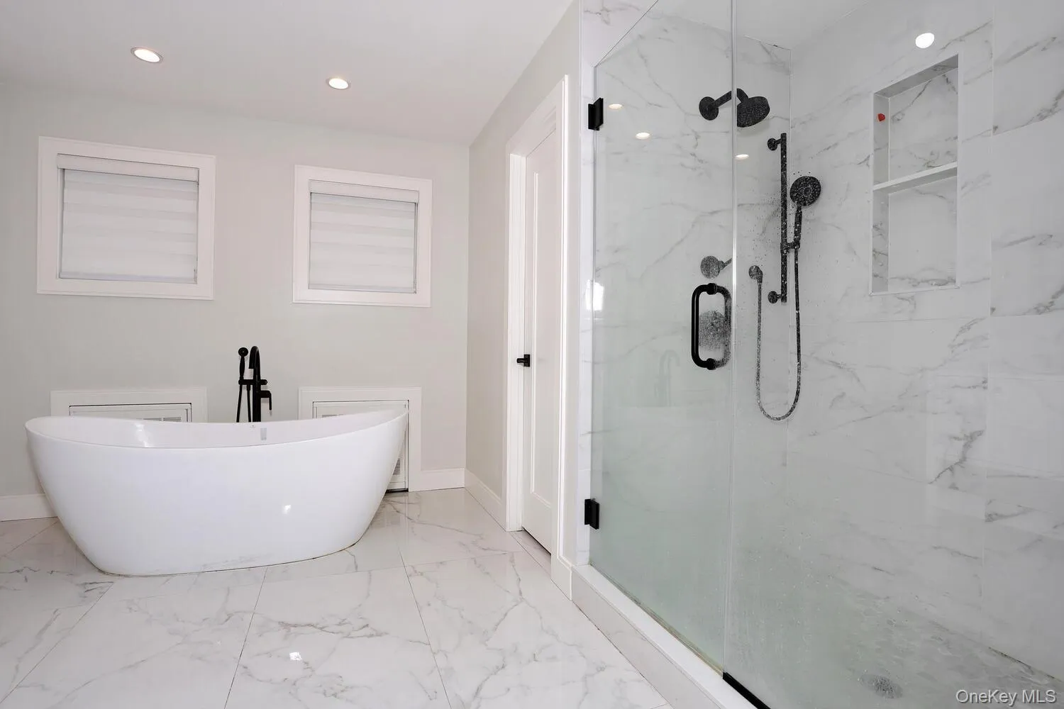 Full bathroom featuring a soaking tub, light marble finish flooring, a marble finish shower, and recessed lighting Full bathroom featuring a soaking tub, light marble finish flooring, a marble finish shower, and recessed lighting