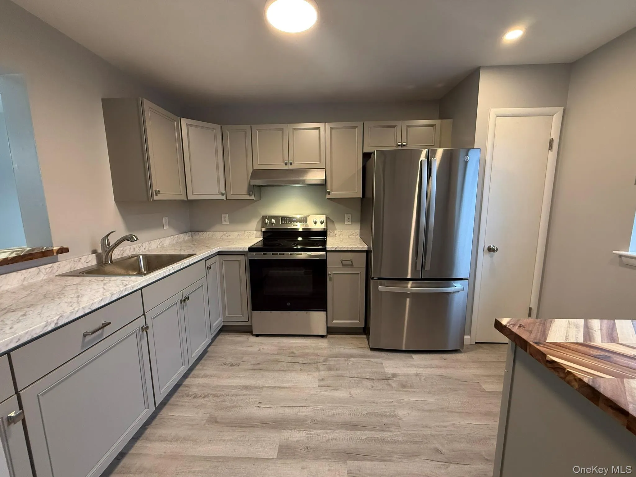 Kitchen with gray cabinets, appliances with stainless steel finishes, light wood-style floors, and recessed lighting Kitchen with gray cabinets, appliances with stainless steel finishes, light wood-style floors, and recessed lighting