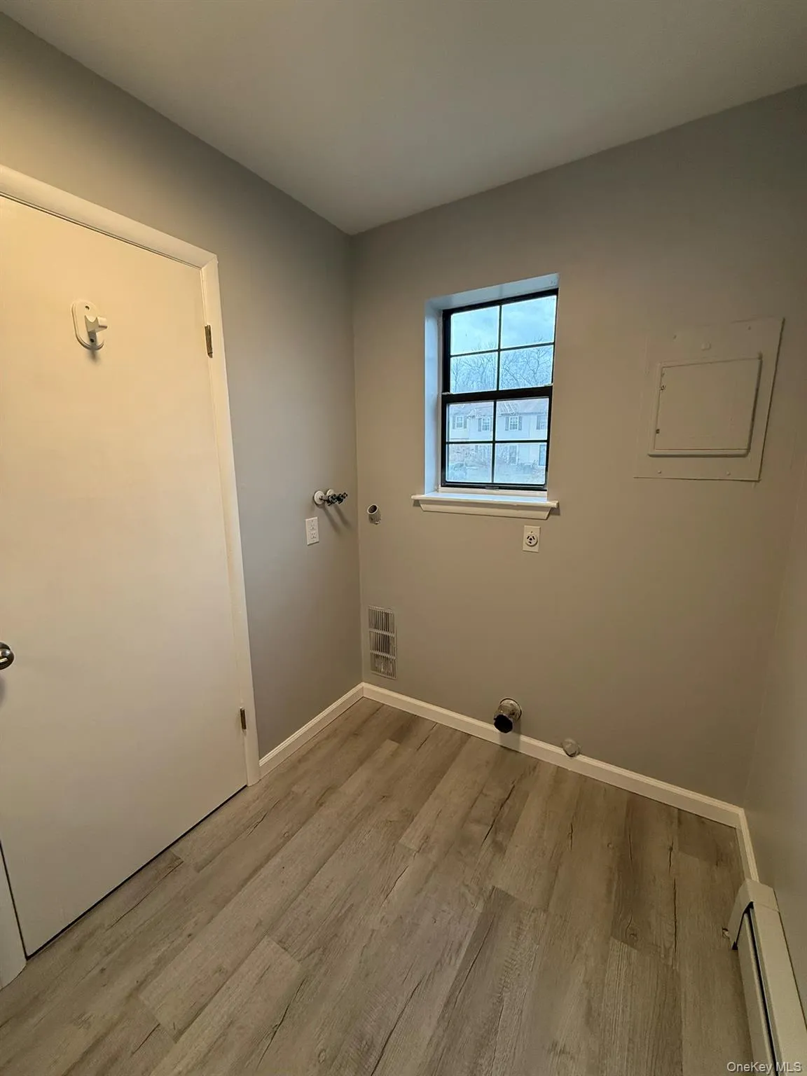 Half bath featuring a baseboard heating unit, light wood-type flooring, electric panel, hookup for dryer, and washer hookup Half bath featuring a baseboard heating unit, light wood-type flooring, electric panel, hookup for dryer, and washer hookup