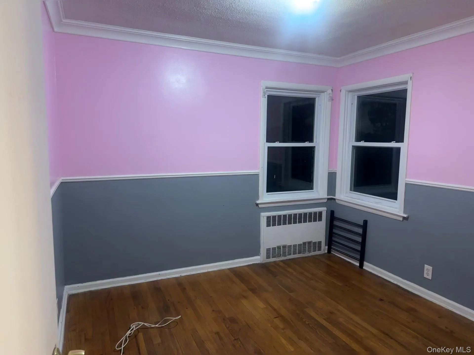 Spare room with radiator heating unit, crown molding, dark wood finished floors, and a textured ceiling Spare room with radiator heating unit, crown molding, dark wood finished floors, and a textured ceiling