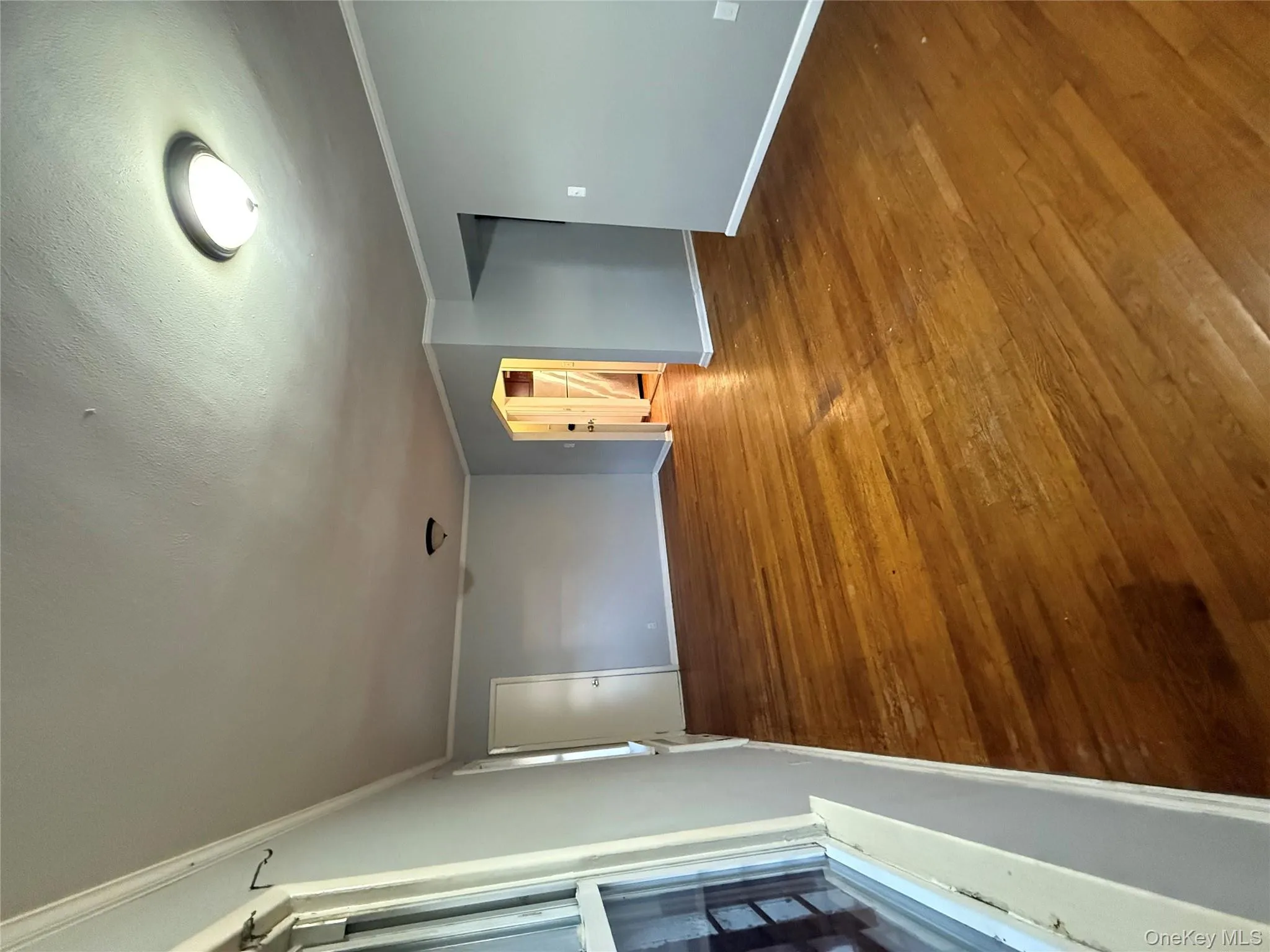 Empty room featuring ornamental molding, wood finished floors, and a textured ceiling Empty room featuring ornamental molding, wood finished floors, and a textured ceiling