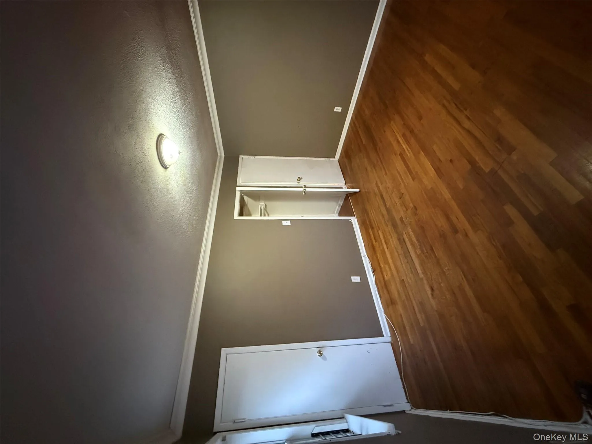 Unfurnished bedroom with crown molding, dark wood-type flooring, a textured ceiling, and a spacious closet Unfurnished bedroom with crown molding, dark wood-type flooring, a textured ceiling, and a spacious closet