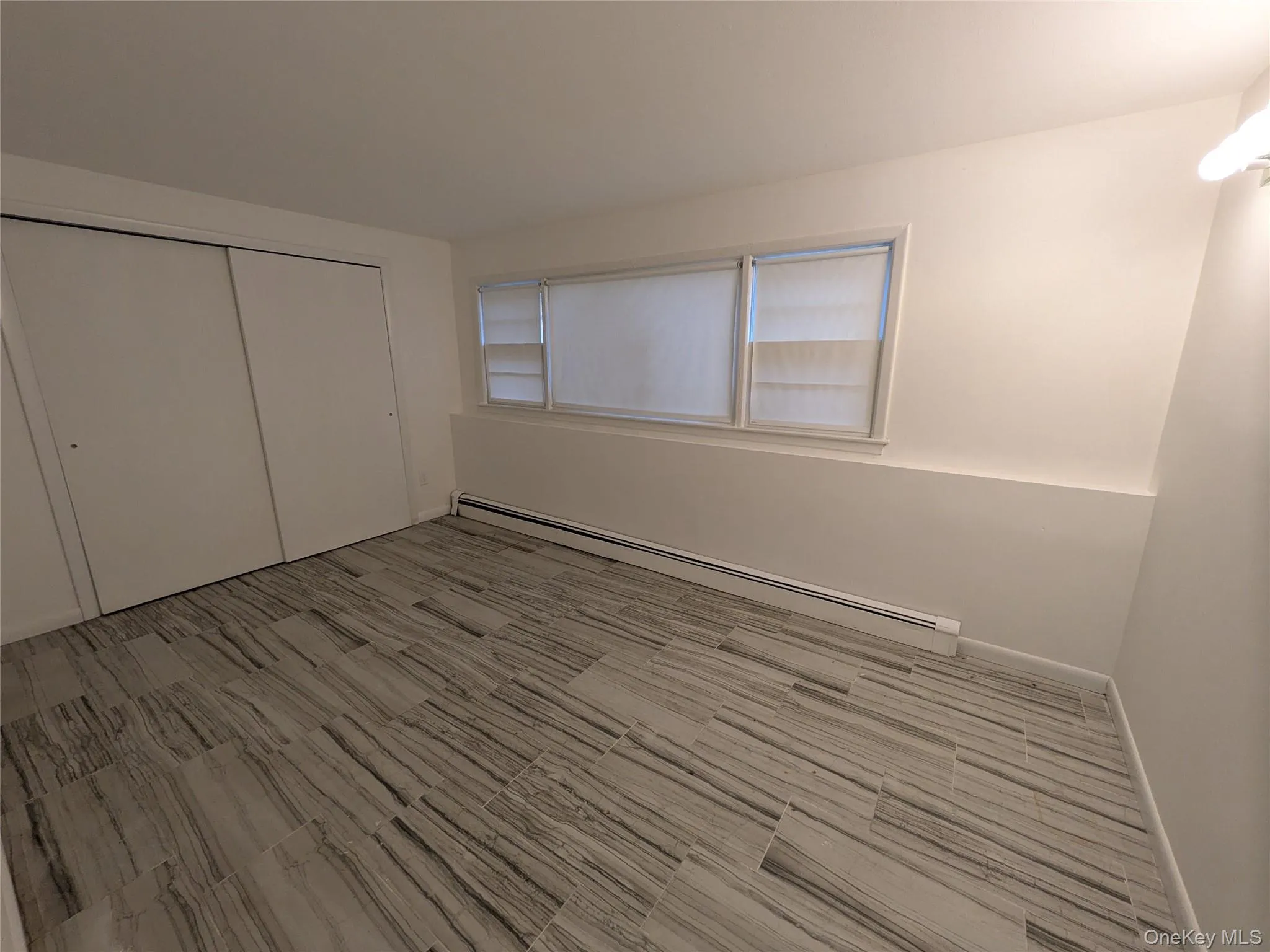 Bedroom in lower level of house with tiled floors, panoramic widow and large double door closet. Bedroom in lower level of house with tiled floors, panoramic widow and large double door closet.