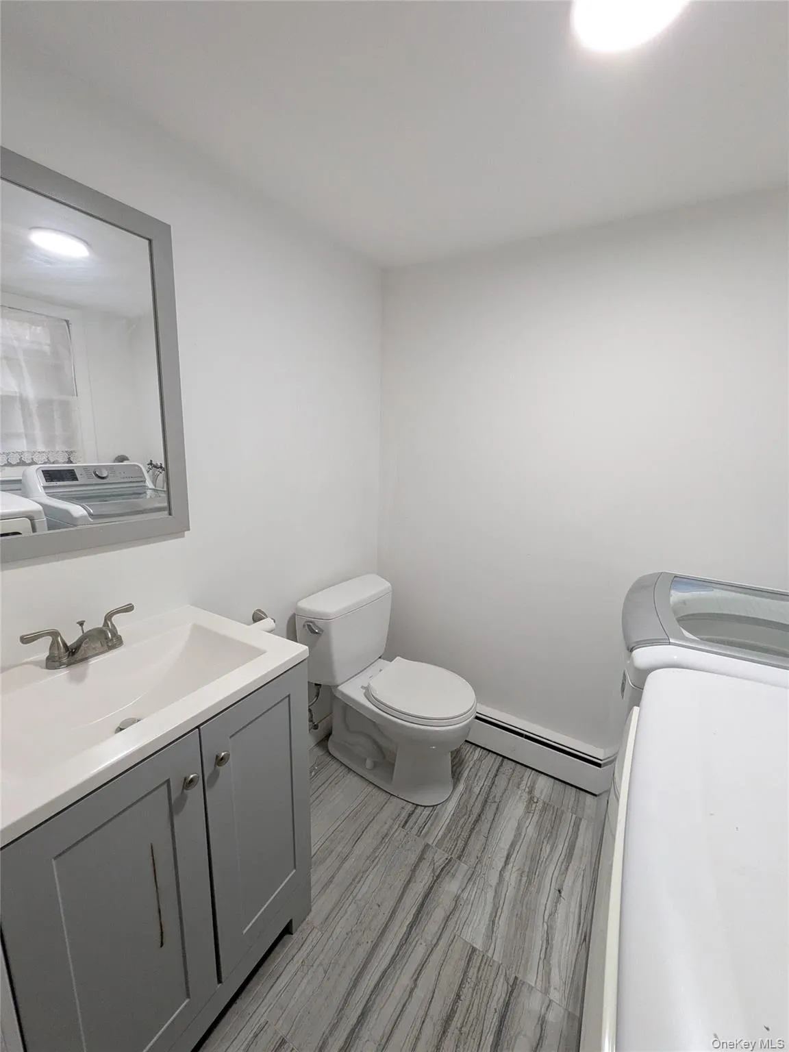 Bathroom with washing machine and clothes dryer, baseboard heating, vanity, and recessed lighting Bathroom with washing machine and clothes dryer, baseboard heating, vanity, and recessed lighting