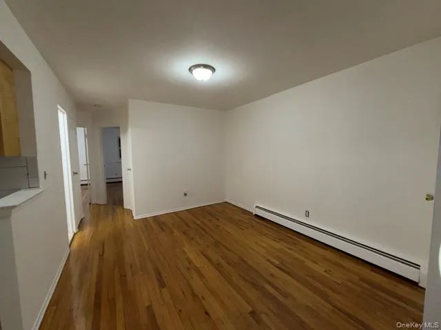 Spare room featuring a baseboard heating unit and dark wood-style flooring Spare room featuring a baseboard heating unit and dark wood-style flooring