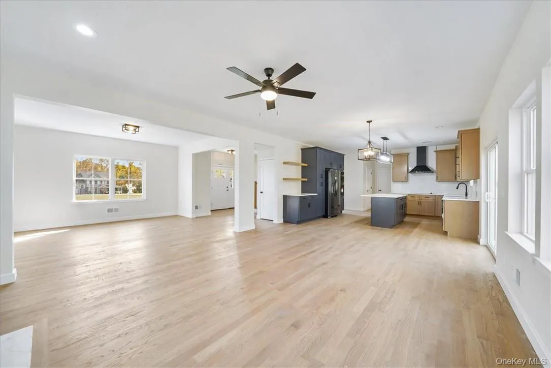 Unfurnished living room with ceiling fan, light hardwood / wood-style flooring, and sink Unfurnished living room with ceiling fan, light hardwood / wood-style flooring, and sink