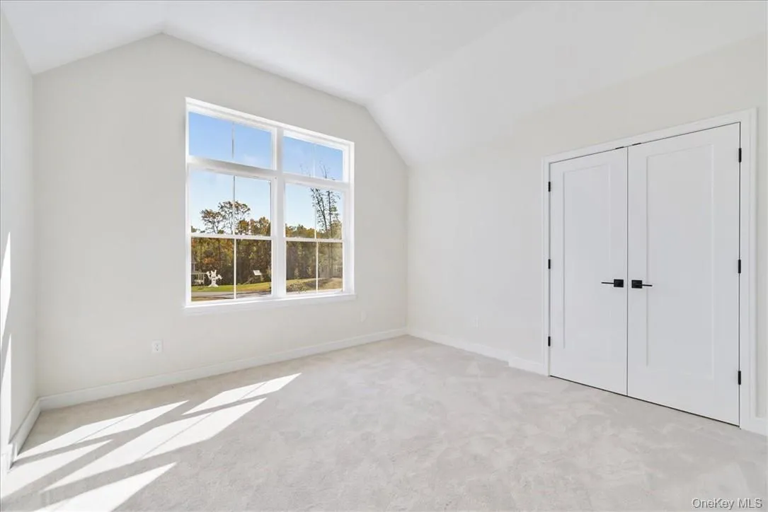 Unfurnished bedroom featuring lofted ceiling, light carpet, and a closet Unfurnished bedroom featuring lofted ceiling, light carpet, and a closet