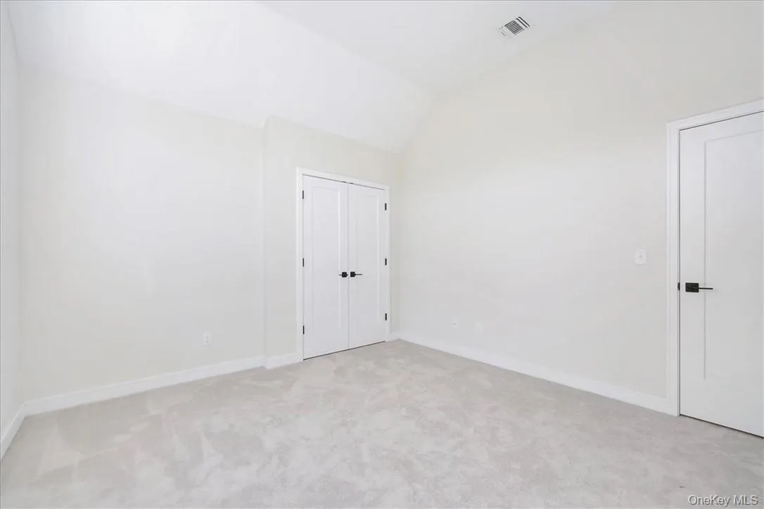 Carpeted spare room featuring vaulted ceiling Carpeted spare room featuring vaulted ceiling