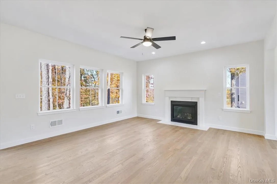 Unfurnished living room featuring a healthy amount of sunlight, ceiling fan, and light hardwood / wood-style flooring Unfurnished living room featuring a healthy amount of sunlight, ceiling fan, and light hardwood / wood-style flooring