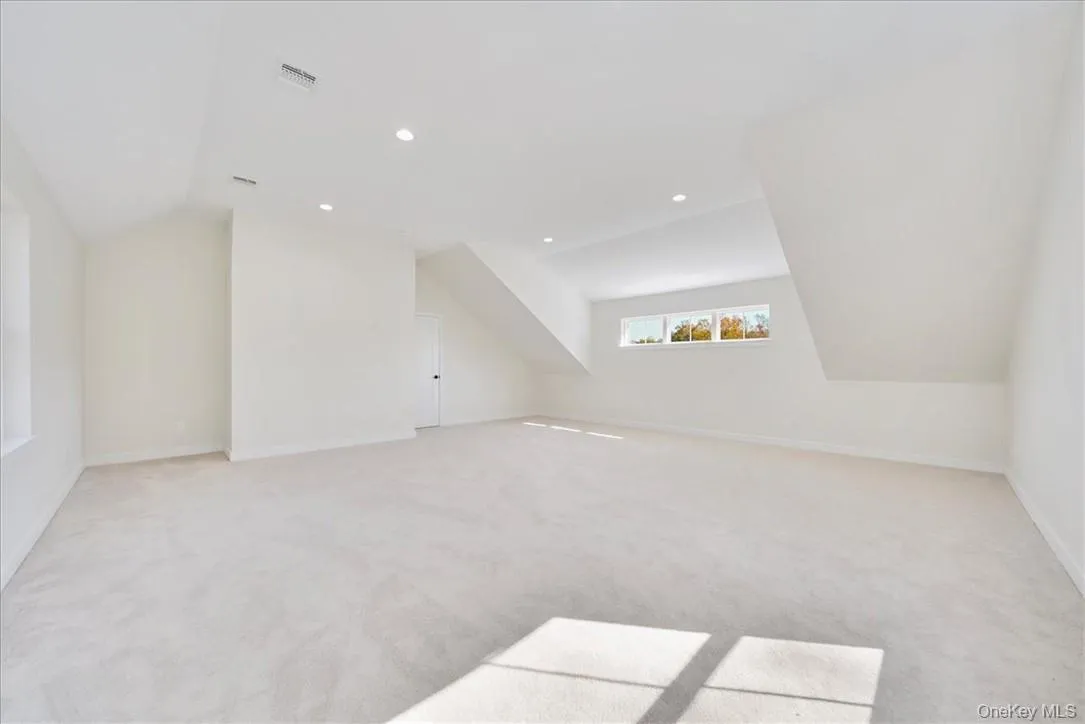 Bonus room with light carpet and vaulted ceiling Bonus room with light carpet and vaulted ceiling