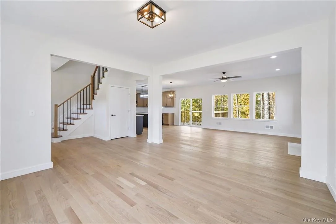 Unfurnished living room with ceiling fan with notable chandelier and light wood-type flooring Unfurnished living room with ceiling fan with notable chandelier and light wood-type flooring