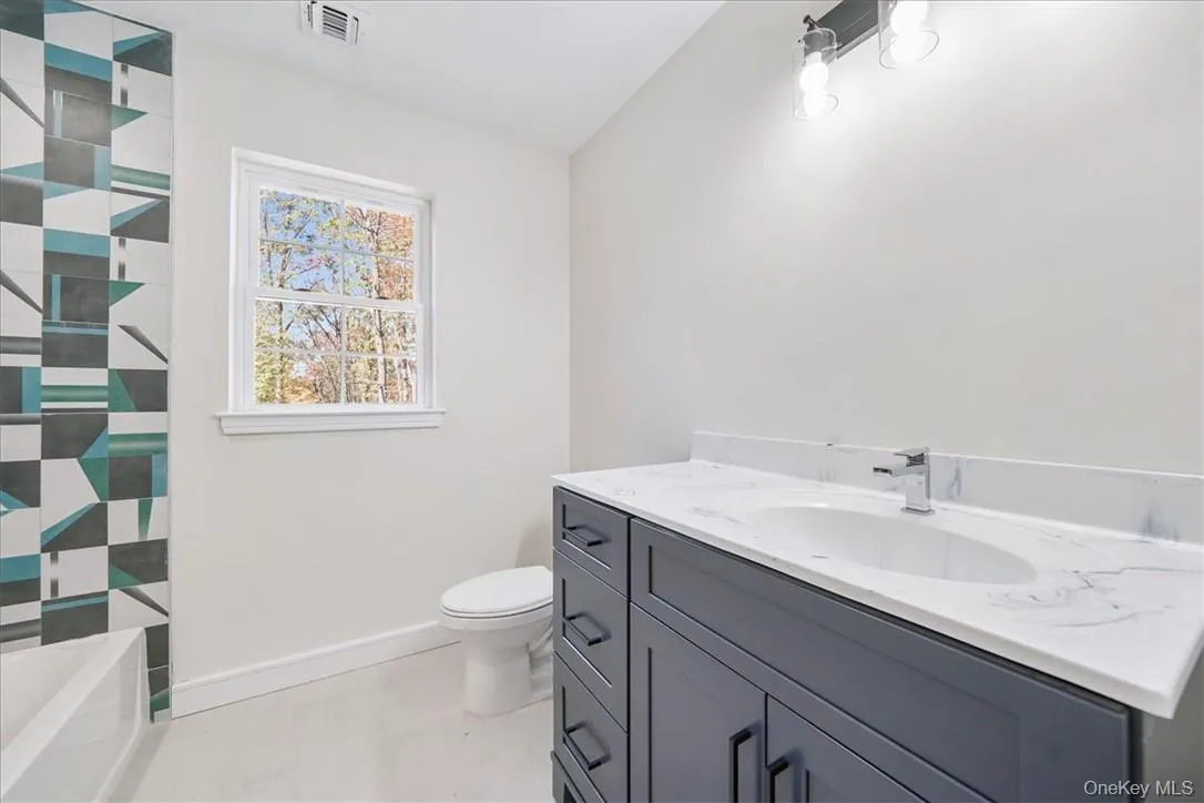 Bathroom with a shower, vaulted ceiling, vanity, and toilet Bathroom with a shower, vaulted ceiling, vanity, and toilet