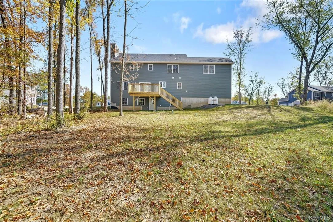 Rear view of house with a yard and a wooden deck Rear view of house with a yard and a wooden deck