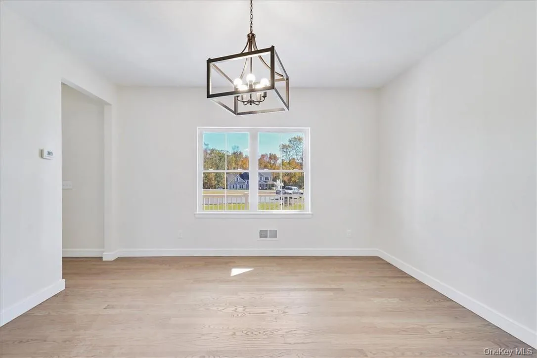 Unfurnished dining area with light wood-type flooring and an inviting chandelier Unfurnished dining area with light wood-type flooring and an inviting chandelier